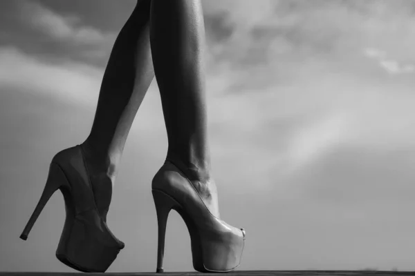 Close-up van jonge vrouwen benen in hoge hakken schoenen. Mooie vrouwelijke benen met hakken op lucht achtergrond. Slanke vrouwelijke benen op hoge hakken. — Stockfoto