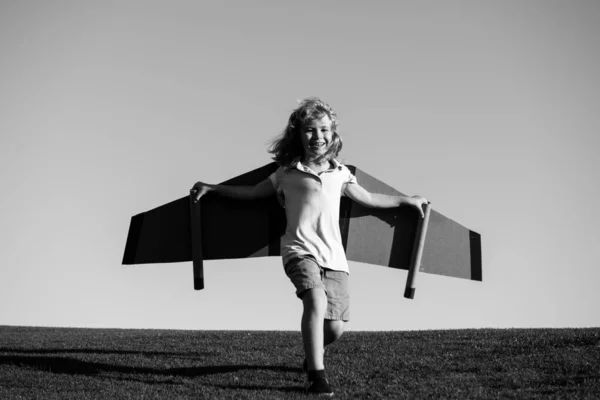 おもちゃの飛行機の翼で遊んでいる子供の男の子。子供たちはパイロットになることを夢見ている。スーパーヒーロー飛行. — ストック写真