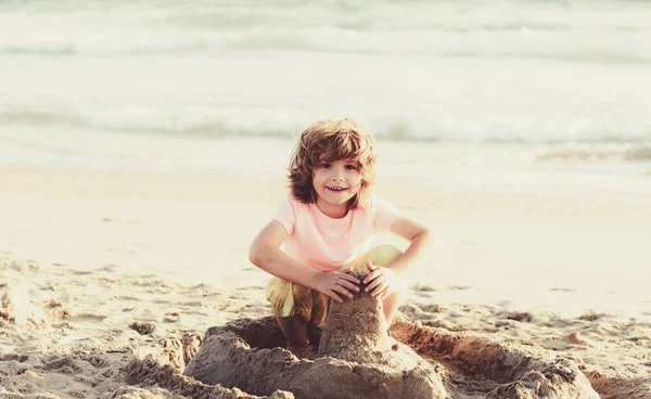 Niño jugando en la playa en las vacaciones de verano. Niño construyendo un castillo de arena en el mar. Niño jugar con la arena en la playa de verano. —  Fotos de Stock