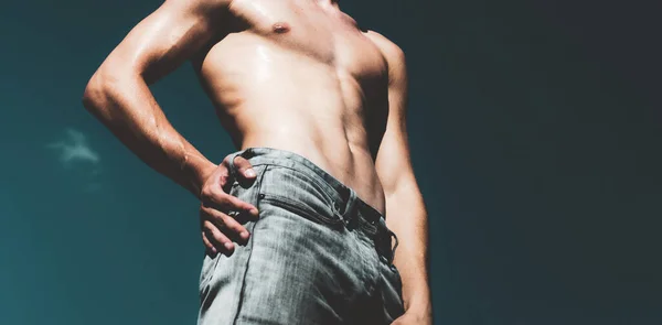 Sexy mannelijk lichaam. Shirtless jongeman jeans op lucht achtergrond. — Stockfoto