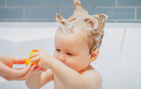 Lächelnd schönes Baby, das in der Dusche badet. Babywäsche im Badezimmer in Schaumstoff. — Stockfoto