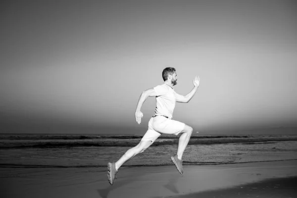 Мужчина бежит по пляжу на закате. Атлетический молодой человек бегает в природе. — стоковое фото