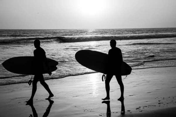 Trópusi tengerparti óceán naplementével vagy napfelkeltével a nyári utazás nyaralás. Szörfös emberek sziluettje, akik a szörfdeszkájukat cipelik a Sunset Beachen. Tengerfenék. — Stock Fotó