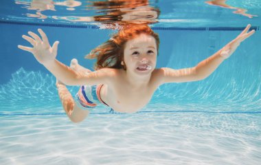 Çocuk yüzme havuzunda yüzüyor, mutlu aktif çocuk dalıyor ve suyun altında eğleniyor, çocuklar su sporu yapıyor. Yaz etkinliği. Sağlıklı çocuk yaşam tarzı. Çocuklarla tropik bir tatil köyünde yaz tatili..