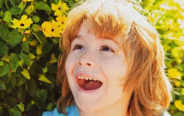 Niño de primavera en el árbol floreciente en el parque de primavera. Niño sonriente al aire libre. Jardín de flores. —  Fotos de Stock