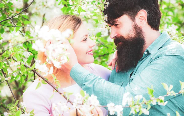 Giovane coppia felice vicino all'albero dei fiori. Gli amanti su una passeggiata in un parco fiorito di primavera. Amare uomo e donna in una passeggiata in un parco fiorito primaverile . — Foto Stock