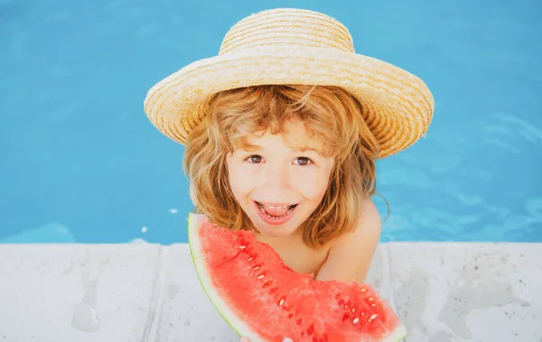 Grabben äter vattenmelon i poolen. Söt pojke äter skiva röd vattenmelon på stranden, glad kaukasisk pojke vattenmelon mot det blå vattnet. — Stockfoto