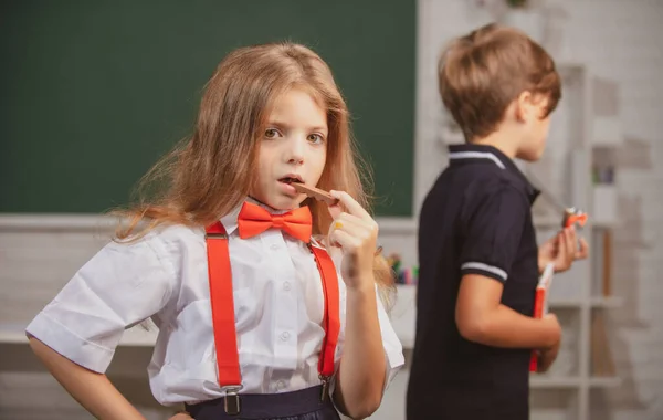 건강에 좋은 음식을 먹거나 초등 학교 교실에서 초콜릿 사탕을 먹는 매력적 인 소녀의 모습. — 스톡 사진