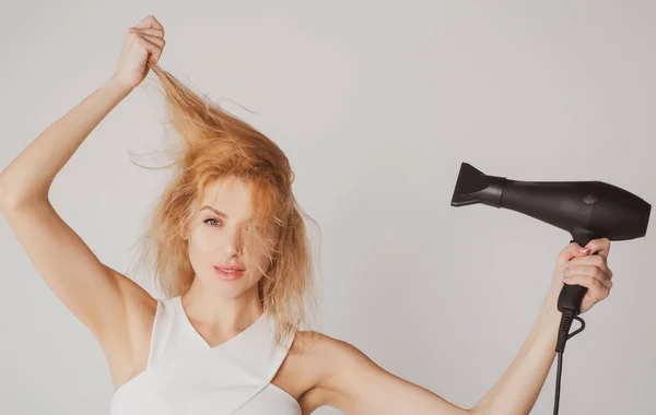 Kvinnan rör hennes hår. Flicka med blont hår med hårtork. Frisyr, frisör koncept. — Stockfoto