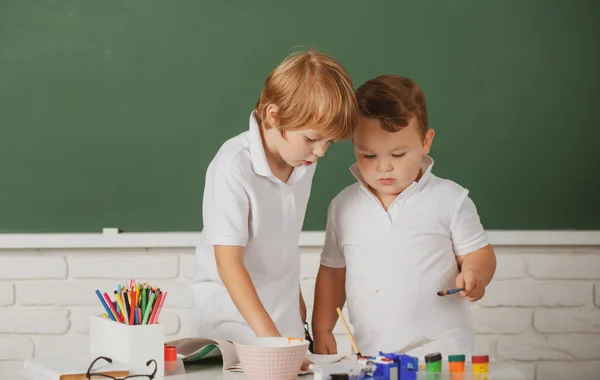 Porträtt skolbarn bossig gör konst läxa, hålla penna, skriva. Barn som går i grundskolan. Måleri skollektion, teckning konst. — Stockfoto