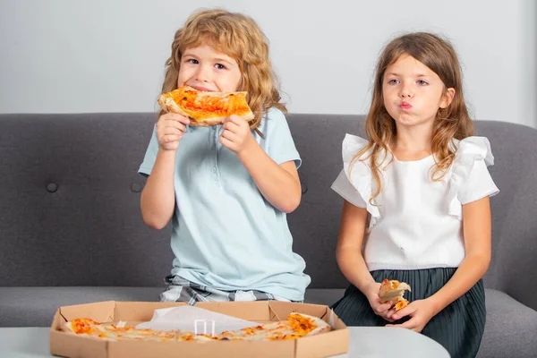 Niños comiendo pizza. Dos niños pequeños muerden pizza adentro. — Foto de Stock