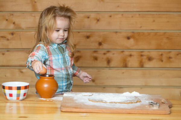 Cooking baby. Kid boy cooks in the kitchen. Little boy puts the dough in a baking dish playing with flour.