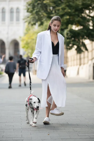Žena chodící se psem, ve stylu ulice. Módní model na ulici. Módní městská výbava. Nenucený styl každodenního oblečení. — Stock fotografie