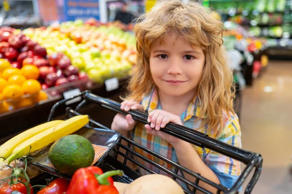 Bambino che acquista frutta al supermercato. Il ragazzo compra verdura fresca in drogheria. Bambini in negozio, cibo sano. Cibo sano per bambini. Bambino nel supermercato compra verdure. — Foto Stock