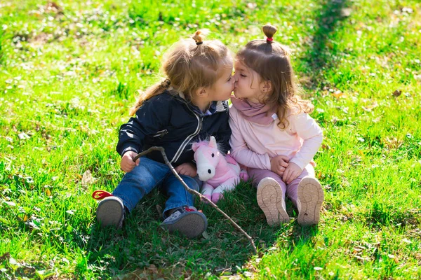 Niedliche Liebe. Kleines Mädchen küsst kleinen Jungen im Park. Lifestyleporträt Kind im Glück draußen auf der Wiese. — Stockfoto