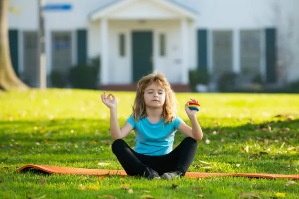 Niño haciendo ejercicio al aire libre. Estilo de vida saludable para niños. Yoga niños en parque haciendo yoga asana. Estilo de vida concepto de relajación, verano armonía al aire libre con la naturaleza. — Foto de Stock