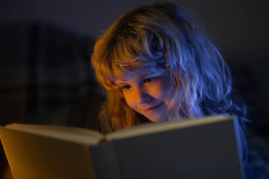 Çocuk kitaptan masal okuyor. Yatakta uzanmış kitap okuyan sevimli bir çocuk. Çocuk yatmadan önce kitap okuyor..