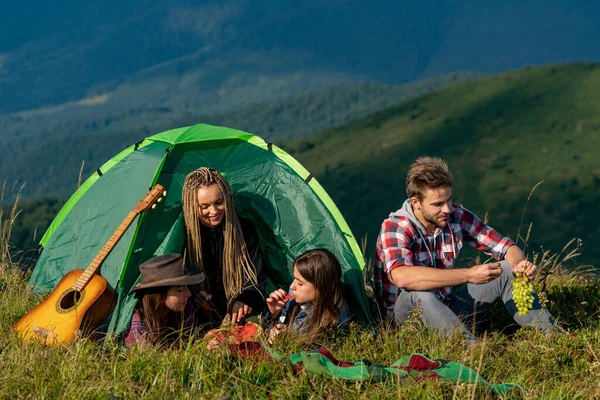 キャンプ旅行の若者。健康的なライフスタイルとエコツーリズム。キャンプで夏の果物を食べるテントの中で幸せな友人のグループ. — ストック写真