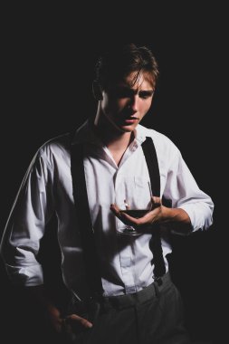 Bardak brendi ya da konyaklı bir adam. Elinde bir bardak viski tutan bir adam. Siyah stüdyoda izole edilmiş viski kadehli bir adamın portresi. Tatma ve degukasyon konsepti. Genç şarap garsonu..