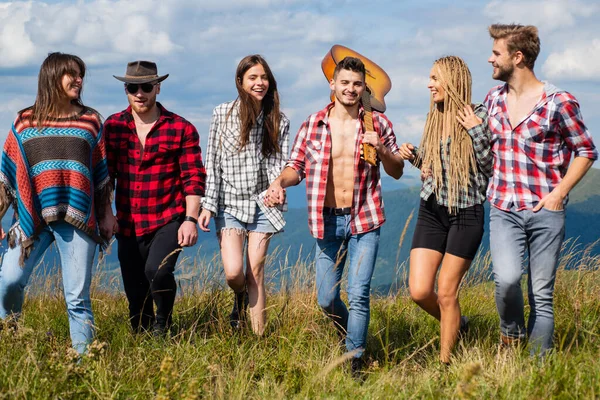山の中を歩く仲間のハイカーのグループ。キャンプ中の若い男性と女性。田舎のハイキング。国の友人のグループは、夏の日に歩く。田舎をハイキングする若者. — ストック写真