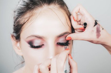 Reklam, dergi. Kirpik çıkarma prosedürü tıkandı. Güzellik salonunda uzun kirpikleri olan bir kadın. Profesyonel makyöz stüdyoda kirpik modelleri boyar..