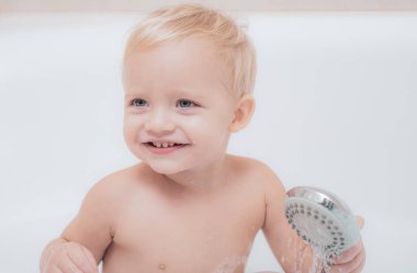 Gülümseyen çocuk oyuncak ördek ile banyoda. Banyo duş altında evde bebek boy gülümseyerek. Küçük çocuk yıkanmasında içinde banyo.