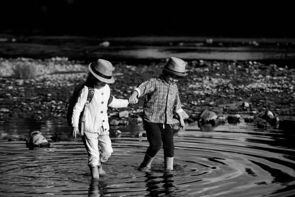 かわいい子供たちが手を取り合って川で遊んでいます。未就学児の男の子と女の子。親友だ。幼児兄弟一緒に上の性質. — ストック写真