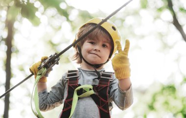 Çocuklar yaz aktiviteleri. Parkta ağaçlara tırmanan bir çocuk. Çocuklar eğleniyor. Sevimli erkek bebek oynuyor. Her çocukluk önemlidir.
