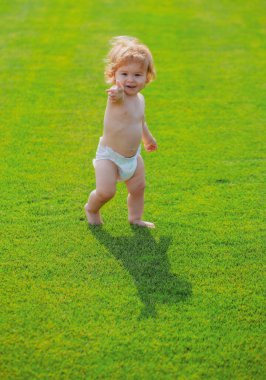 Sevimli komik çocuk emeklemeyi öğreniyor, bahçede çocuk bezi pantolonuyla oynarken eğleniyor..