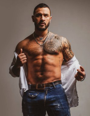 Dövmeli, vahşi, yakışıklı bir adam. Erkekler sıradan dövmeler yaptırır. Acımasız yakışıklı erkek modelin portresi. Düğmesiz gömlekli kaslı seksi erkek. Seksi, çıplak gövdeli yakışıklı adam..
