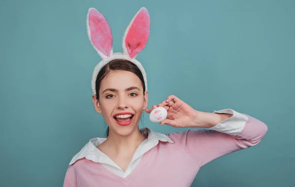Καλό Πάσχα. Νεαρή γυναίκα με αυτιά κουνελιού. Πορτρέτο μιας ευτυχισμένης γυναίκας με αυτιά κουνελιού. Εκτύπωση φιλιού κραγιόν στο αυγό του Πάσχα. — Φωτογραφία Αρχείου