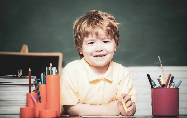W domu albo w szkole. Portretowe dziecko z podstawówki. Chłopiec ze szkoły podstawowej na podwórku szkolnym. Wesoły uśmiech dziecka na tablicy. — Zdjęcie stockowe