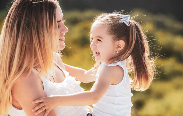 Mother love. Happy woman and little girl daughter smiling. Happy family mother and child daughter hugging and kissing. Lifestyle portrait mom and daughter in happy mood at the outside. — Stock Photo, Image