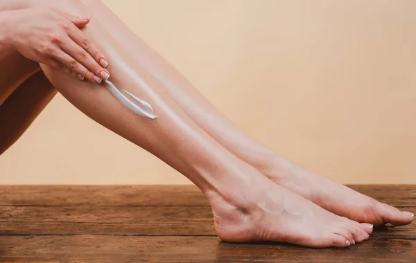 Young woman applying body lotion on legs. Cosmetic cream on woman leg with clean soft skin. Applying moisturizer cream on legs. Cellulite or anti cellulite treatment. Body care and spa salon concept. — Stock Photo, Image