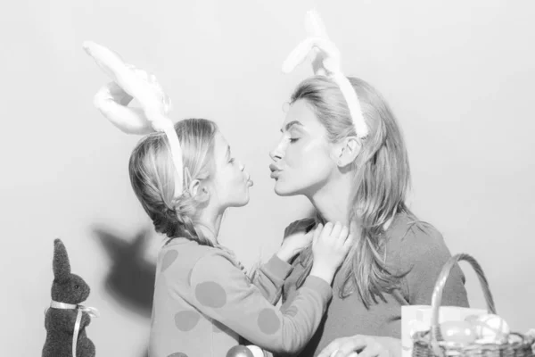 Família feliz se preparando para a Páscoa. Bonito menina e mãe usando orelhas de coelho. Mãe e filha beijo. — Fotografia de Stock