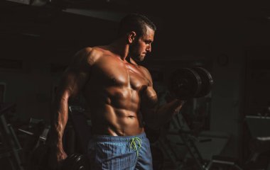 Vücut geliştirici, spor salonunda dambıl egzersizleri yapıyor. Gövdesiz sporcu. Sportif egzersiz. Atletik vücut.