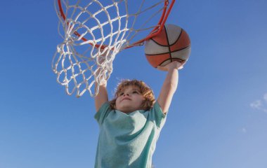 Basketbolcu çocuklar basketbolcu Slam Smaç. Basketbolcu heyecanlı çocuğun yakın plan görüntüsü topu batırması, stok fotoğrafı. Gökyüzü arka planında izole edilmiş pankart.