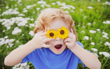 Komik çocuk dışarıda eğleniyor. Çocuk yaz parkında oynuyor. Yeşil çimlerin üzerinde küçük bir çocuk.