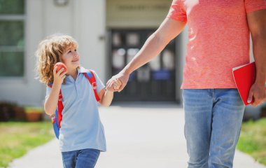 Baba ve oğul babalarıyla koşuyor okuldan dönüyorlar. Aile, eğitim ve açık hava konsepti. Babam okula çocuğuyla birlikte gidiyor..