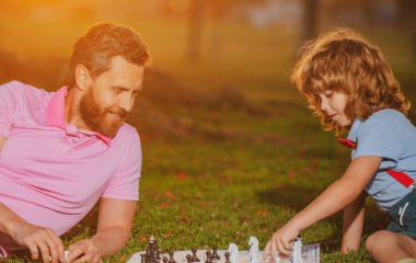 Baba ve oğul dışarıda satranç oynuyorlar. Erkekler satranç oynamayı sever. Erkek üretim portresi.