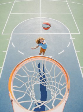 Basketbol formalı çocuk basket sahasında basket topuyla zıplıyor..