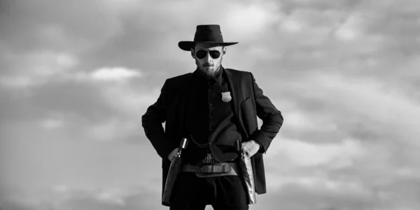 Siyah takım elbiseli ve kovboy şapkalı şerif, afiş. Vahşi batı, batı, klasik tabanca tabancası ve mühimmatı olan adam.. — Stok fotoğraf