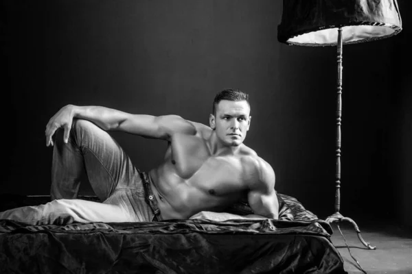 Çıplak gövdeli seksi erkek vücut geliştirme sporcusu portresi iç çamaşırlı yastıkların üzerinde yatıyor.. — Stok fotoğraf