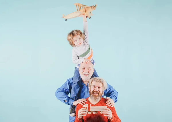 Tre generationer gamla farfar och son leker med leksaksplan i studion. Isolerad bakgrund. — Stockfoto