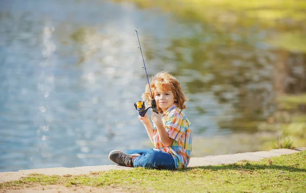 幸せな子供時代。湖で子供釣り。川でスピナーを持つ少年。釣りの概念. — ストック写真