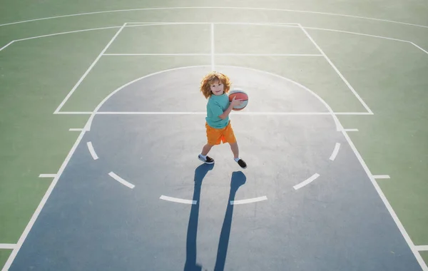 Criança menino se preparando para tiro de basquete, ao ar livre no parque infantil. — Fotografia de Stock