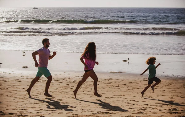 Baba, anne ve çocuk sahilde koşuyor. Sağlıklı aile hayatı kavramı. Yaz insanları denizde tatil yapar. Spor aktivitesi, aile kavramı. — Stok fotoğraf