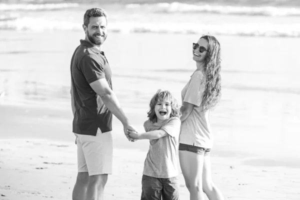 海のビーチに沿って家族の散歩。ビーチで遊んでいる子供と幸せな両親。自然の中で夏の時間を過ごす. — ストック写真