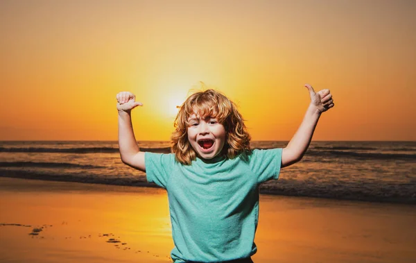 日没のビーチで子供の男の子、手を挙げた。驚くべき子供の感情. — ストック写真