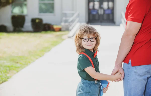 Father and son walking trough school park. Portrait of happy nerd pupil holding teachers hand. — Stock Photo, Image